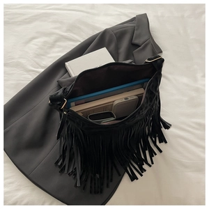 Macro view of a black fringe shoulder bag showing large capacity for tablets and books