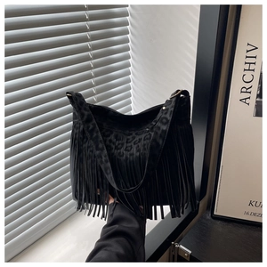 Detailed view of black tote bag featuring leopard texture and long fringe tassels