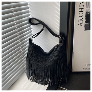 Macro view of black tassel shoulder bag featuring leopard pattern texture and gold buckle