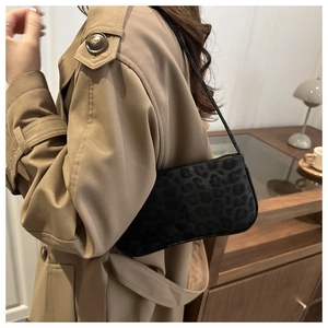 Close-up of black leopard print underarm bag with slim shoulder strap on model
