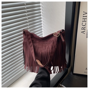 Detail of burgundy fringe shoulder bag featuring long tassels and adjustable strap