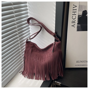 Close-up of vintage burgundy suede shoulder bag with long tassel fringe and hobo shape