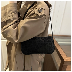 Detail of black leopard print baguette bag on trench coat with long shoulder strap