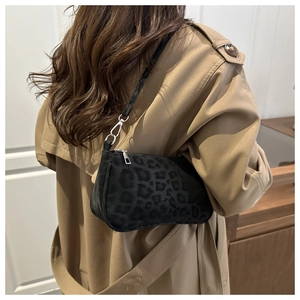 Close-up of black leopard print suede underarm bag with silver zipper on trench coat