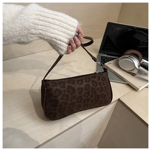 Détail d'un sac baguette léopard sur un bureau avec un ordinateur et un casque