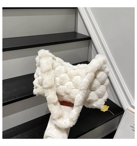 Detail of white plush checkered handbag with gold zipper in a modern indoor setting