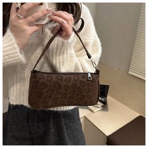 Close-up of a brown leopard print baguette bag with a sleek metal zipper and slim strap