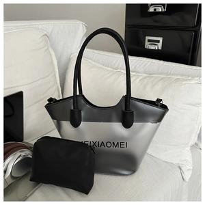 Détail du sac cabas en PVC argenté avec pochette interne et logo sur canapé