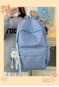 Detailed side view of blue and white checkered backpack with plush monster pendant