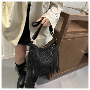 Detail of black suede tote bag with leopard print, fringe tassels, and bohemian style
