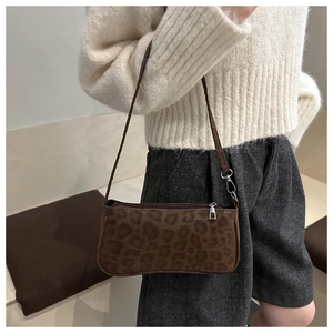 Detail shot of leopard print handbag with zipper closure and brown leather shoulder strap