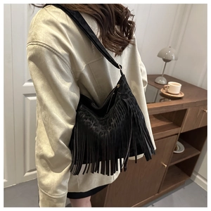 Close-up of black matte shoulder bag with long fringe tassels and leopard texture details