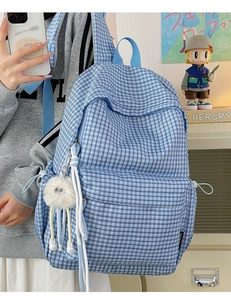 Detail of blue checkerboard backpack on model featuring a white plush monster charm