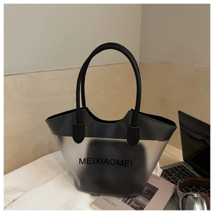 Détail du sac cabas en PVC dépoli avec anses en cuir et pochette interne sur un bureau