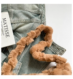 Detail of soft brown plush strap with metal button on blue denim fabric background