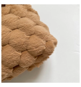 Close-up of brown plush faux fur fabric with quilted semi-circle pattern texture
