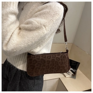 Close-up of leopard print shoulder bag worn with white knitwear for fashion style