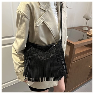 Detail of black tassel crossbody bag with leopard texture and zip closure on model