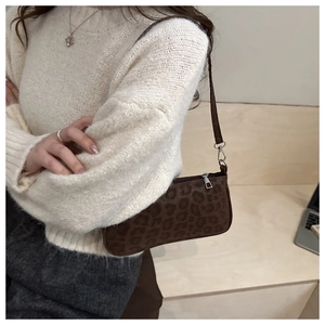Close-up of leopard print shoulder bag worn with a white sweater in a modern setting
