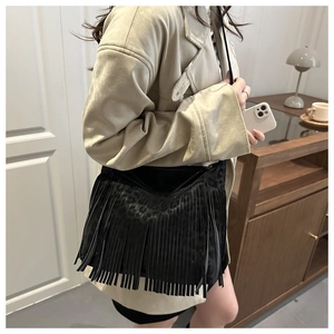 Detail of black fringe shoulder bag with leopard print texture and metal zipper closure