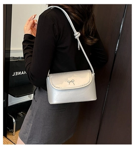 Close-up of metallic silver shoulder bag with detailed bow buckle and knotted strap