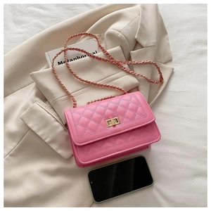 Detailed view of pink quilted crossbody bag with gold twist lock and chain strap