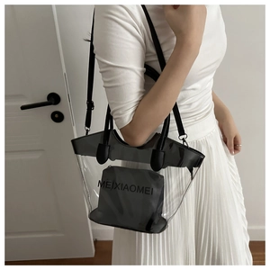 Détail d'un sac cabas transparent en PVC avec garniture en cuir noir porté par un mannequin