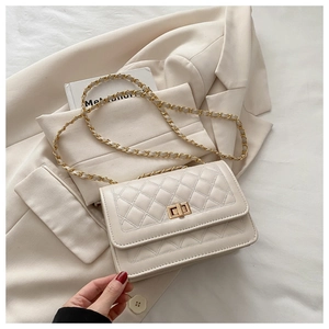 Close-up of cream quilted crossbody bag featuring golden turn-lock and chain strap