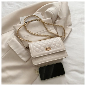 Détail d'un sac bandoulière matelassé beige avec fermoir doré et bandoulière chaîne