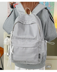 Detail of black and white checkered backpack with fluffy pendant and large main pocket