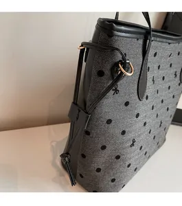 Détail d'un cabas en tissu gris à chevrons avec pois noirs et anneaux dorés brillants