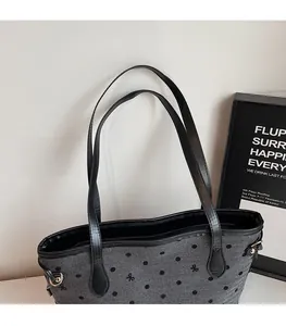 Gros plan d'un sac cabas gris à pois avec des anses en cuir noir et des boucles en métal doré