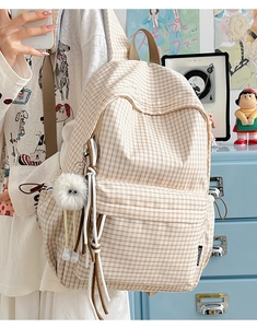 Detail of checkered vintage backpack featuring plush monster charm and side pockets