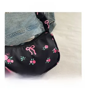 Close-up of floral canvas underarm bag with pink roses and bow details on white fabric