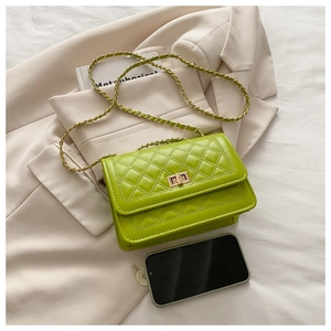 Macro view of bright green quilted flap bag with gold twist lock and chain strap