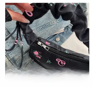 Detailed view of silver metal zipper and rose pattern on black fabric shoulder bag