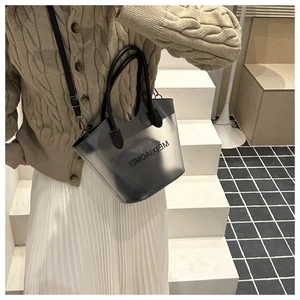 Détail d'un sac cabas en PVC gris translucide avec bandoulière sur un mannequin féminin