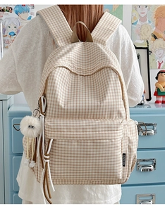 Detail of vintage beige plaid backpack with plush ball charm and large storage capacity