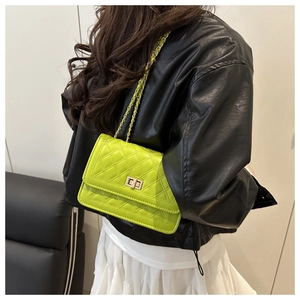 Detailed view of bright green quilted crossbody bag with gold-tone lock worn by model