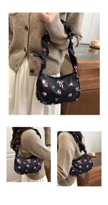 Detail of black floral underarm bag with pink roses and ruffled scrunchie shoulder strap