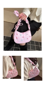 Detailed view of a pink floral shoulder bag with elegant satin bow straps and red rose patterns