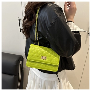 Detail of neon green quilted crossbody bag with gold chain and twist lock on model