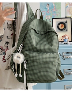 Detail of green plaid backpack featuring front pocket and cute plush toy accessory