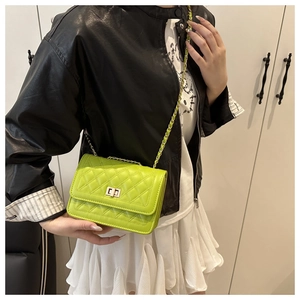 Detail of neon green quilted bag with golden twist lock and chain strap on shoulder