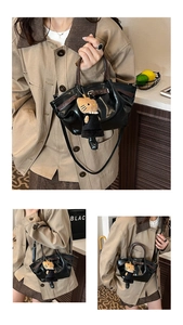 Detail of black glossy faux leather handbag featuring pleats and cute cat plush charm