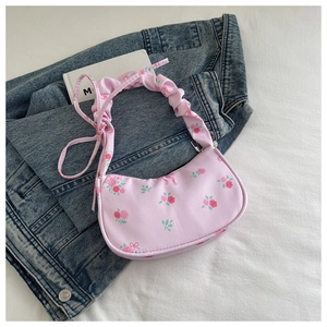 Detailed view of pink floral shoulder bag with rosette print and ruched cloud handle