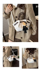 Macro detail of white pleated bucket bag featuring dark brown handles and cute plush charm