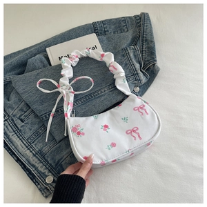 Close-up of white canvas bag with pink rose patterns and decorative ribbon charm