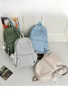 Collection of plaid canvas backpacks in green, blue, and beige with fuzzy ball charms