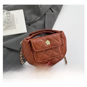 Detailed view of brown quilted crossbody bag with golden floral clasp and chain strap